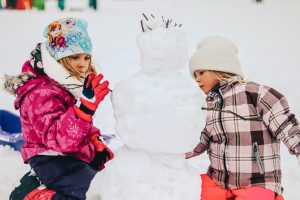 montagna con bambini che fanno pupazzo di neve